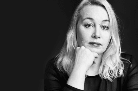 Ann Heberlein i ett svartvitt, allvarligt, porträtt mot en svart bakgrund.