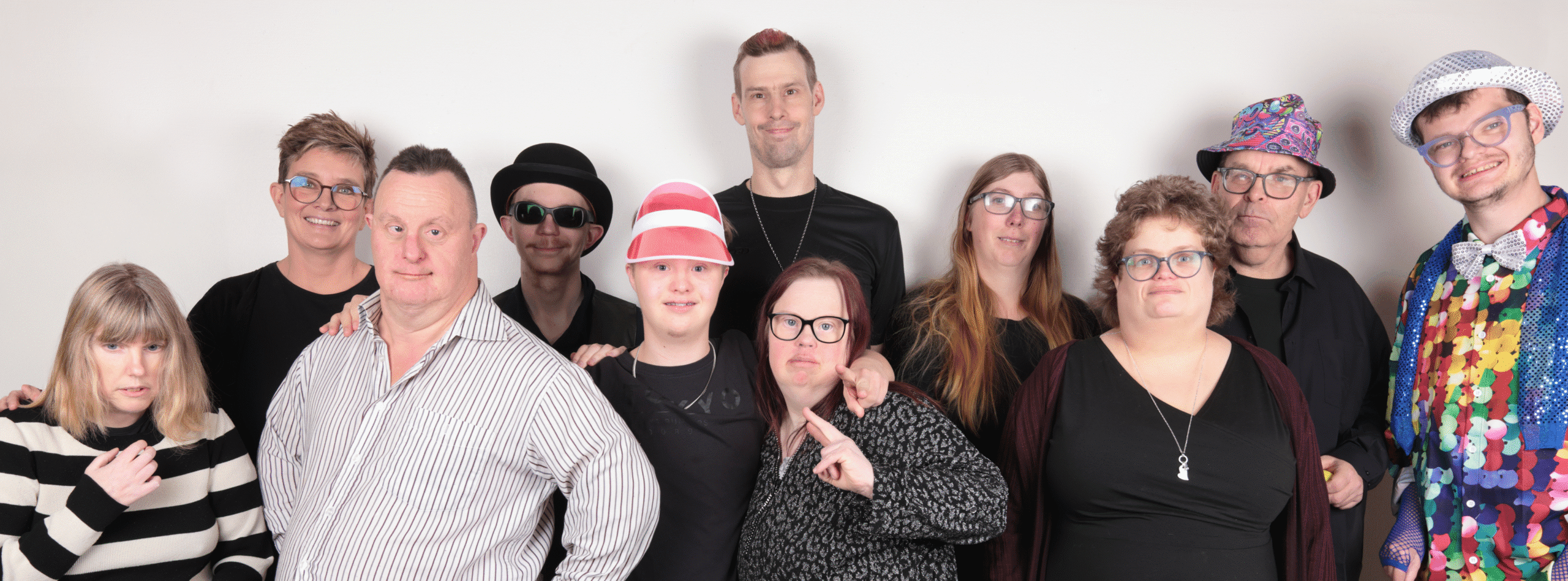 MusikSkaparna tillsammans med sin ledare Camilla uppställda mot en vit vägg.