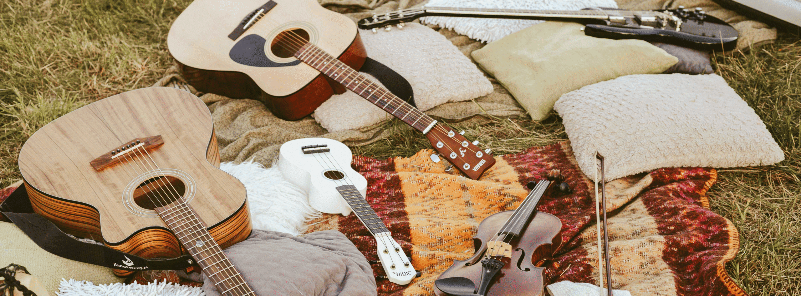 Gitarrer, fioler och ett keyboard ligger bland filtar och kuddar i gräset.
