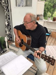 Jonny Jonny de Crapetz spelar på sin gitarr och tittar när i en pärm.
