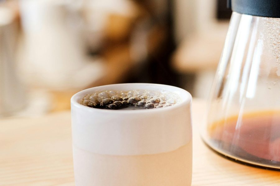 Bild på en fylld kaffekopp med med kaffekanna i bakgrunden